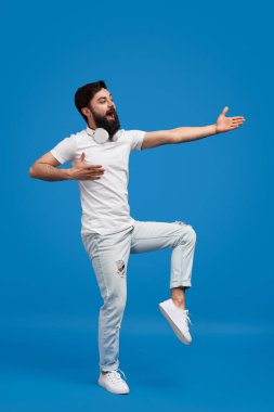 Sakallı adam şarkı söylüyor ve dans ediyor