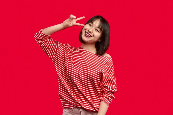 Cheerful Asian woman gesturing V sign — Stock Photo, Image