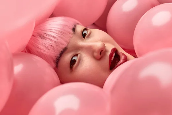 Amazed Asian woman under pink balloons — Stock Photo, Image