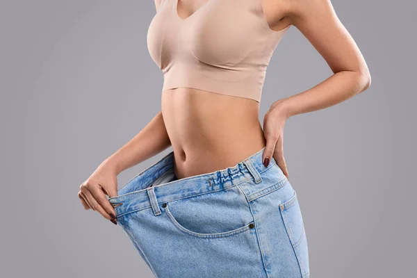 Crop fêmea puxando jeans oversized na cintura fina — Fotografia de Stock