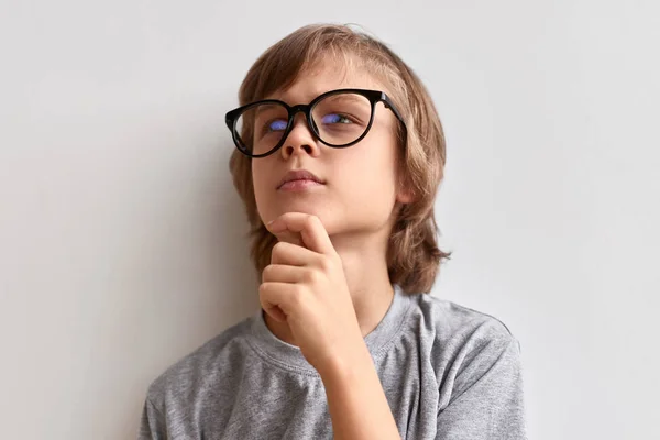 Thoughtful schoolboy rubbing chin — Stock Photo, Image
