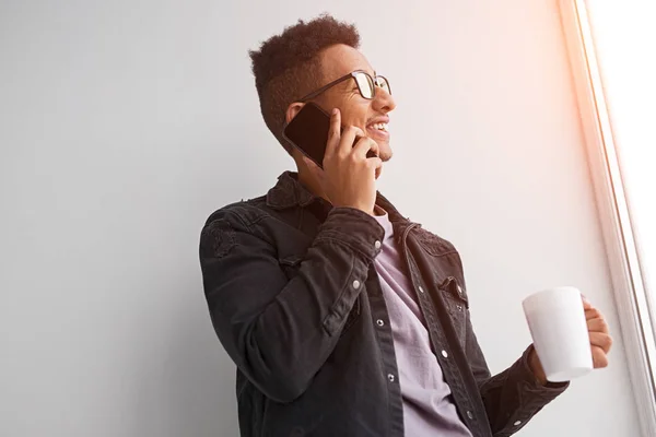 웃고 있는 흑인 남자가 전화통화를 하고 커피를 마시며 — 스톡 사진