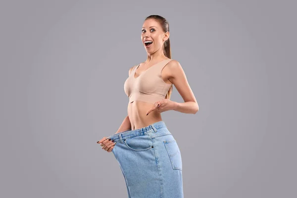 Aufgeregte Dame zeigt auf übergroße Jeans — Stockfoto