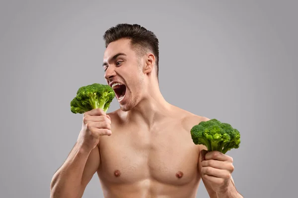Uomo affamato mangiare broccoli sani — Foto Stock