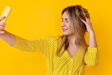 Saçlarını buruşturan ve selfie çeken bir kadın.