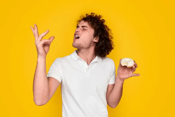 Молодий чоловік дегустує смачний пончик — стокове фото