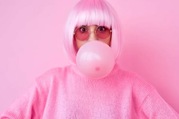 Mujer joven en traje rosa que sopla goma de mascar — Foto de Stock