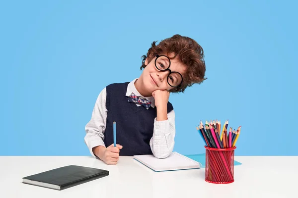 Cute schoolboy sitting at desk — Stock Photo, Image