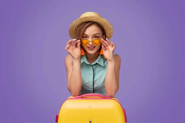 Viajero femenino con maleta ajustando gafas de sol — Foto de Stock