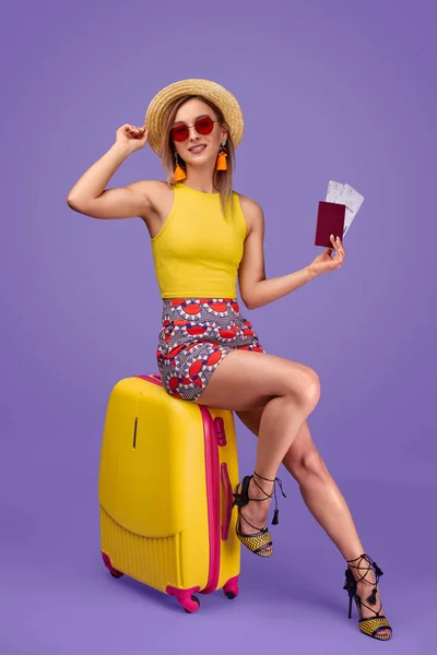 Женщина-путешественница с билетами сидит на чемодане — стоковое фото