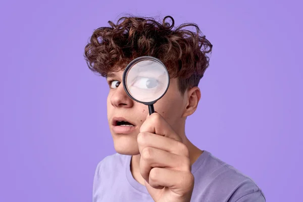 Funny teenager looking through magnifying glass — Stock Photo, Image