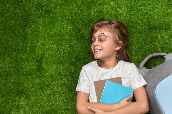 Lachende school jongen liggend op gras en op zoek weg — Stockfoto