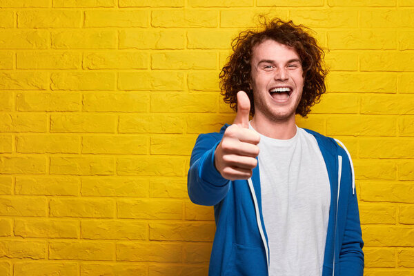 Cheerful young man showing thumb up