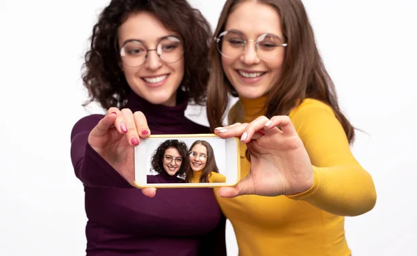 Amis féminins montrant smartphone pendant selfie — Photo