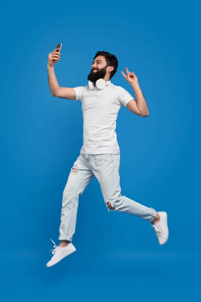 Homem barbudo pulando e tirando selfie — Fotografia de Stock