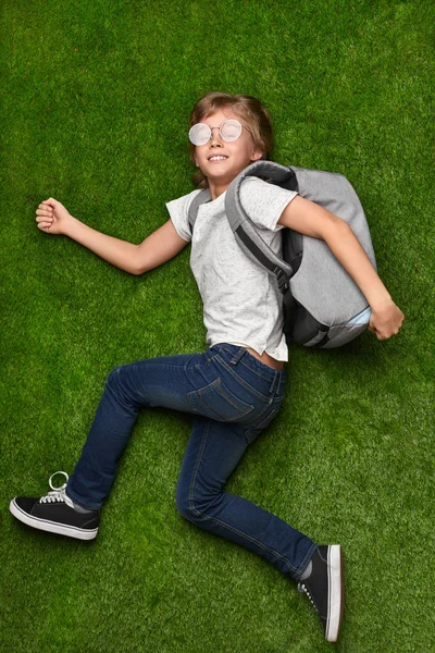 Веселый школьник бежит учиться на лужайку — стоковое фото