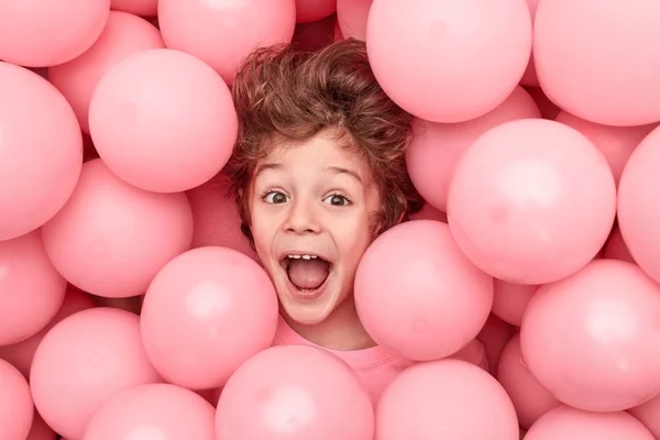 Upphetsad pojke som ligger i ballonger — Stockfoto