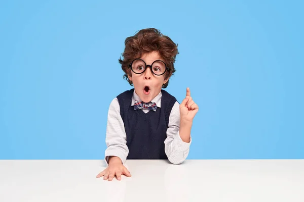 Surprised schoolboy sitting at desk — Stock Photo, Image