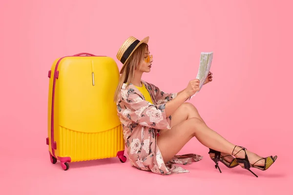 Trendy traveler reading map near luggage — Stock Photo, Image