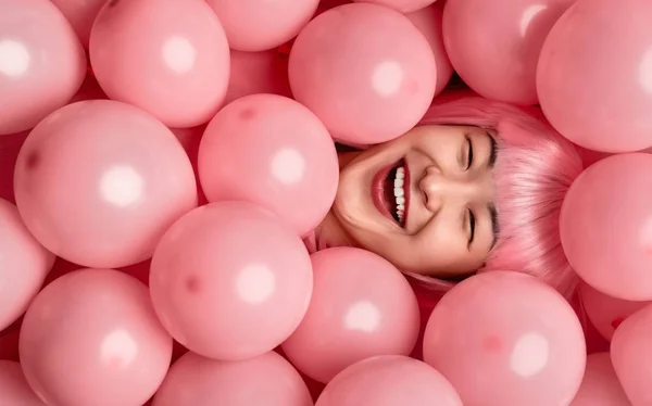 Asiática mujer riendo bajo rosa globos — Foto de Stock
