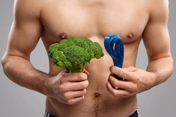 Crop ragazzo muscolare con broccoli e metro a nastro — Foto Stock