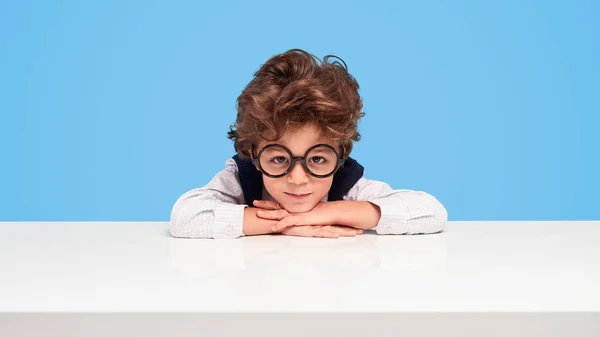 Nerdy schoolboy sitting at desk — Stock Photo, Image