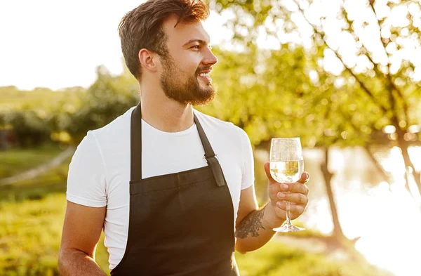 Homem sorridente com copo de vinho no campo — Fotografia de Stock