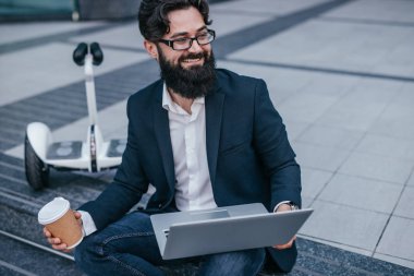 Laptop ve sıcak içecek ile neşeli işadamı