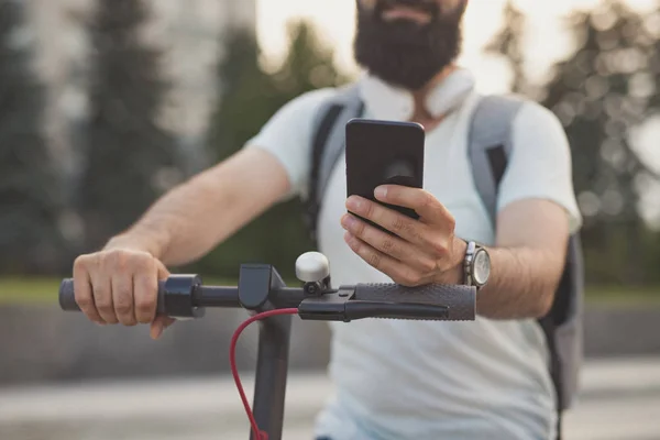 Crop hipster met smartphone op scooter — Stockfoto