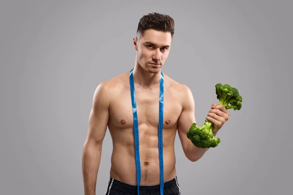 Serieuze man die met broccoli traint — Stockfoto