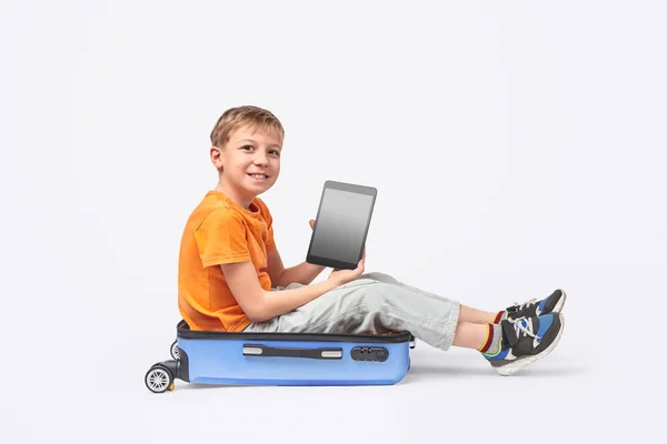 Веселый мальчик с табличкой сидит в чемодане — стоковое фото