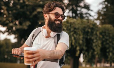 Parkta elektrikli araç sürme sıcak içecek ile Gülümseyen hipster