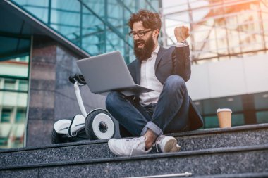 Neşeli piyango talihlisi merdivenlerde oturuyor