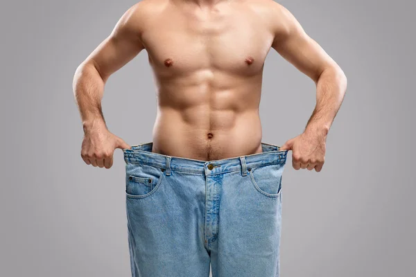 Cultivo hombre mostrando el progreso de pérdida de peso —  Fotos de Stock