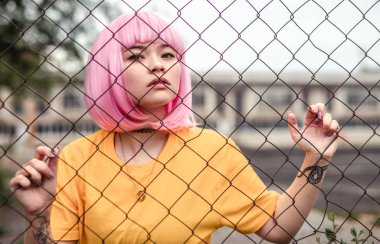 Net çit arkasında boyanmış saçları ile genç hipster