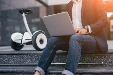 Kırpma işadamı gyroscooter yakın dizüstü bilgisayar kullanarak