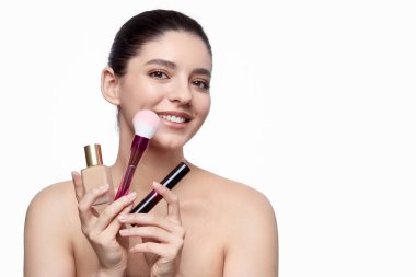 Makyaj malzemeleri gösteren gülümseyen kadın