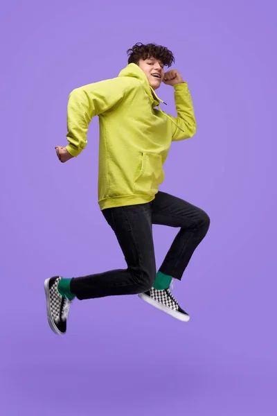 Teenager jumping high on purple background — Stock Photo, Image