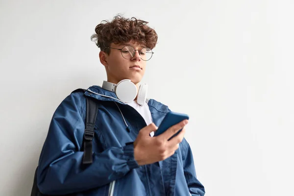 Nastolatek za pomocą smartfona w pobliżu ściany — Zdjęcie stockowe