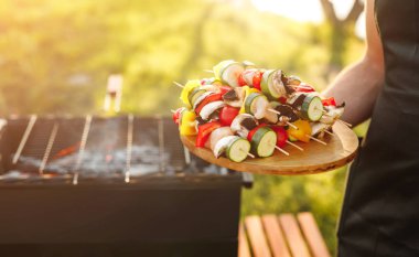 Izgara için ahşap çubuklar üzerinde sebze taşıyan yüzsüz aşçı