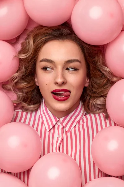 Beautiful woman in balloons licking lips — Stock Photo, Image