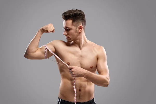Сильный мужчина измеряет мышцы рук — стоковое фото