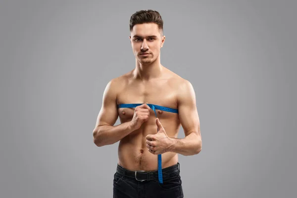 Hombre midiendo pecho y señalando pulgar hacia arriba — Foto de Stock