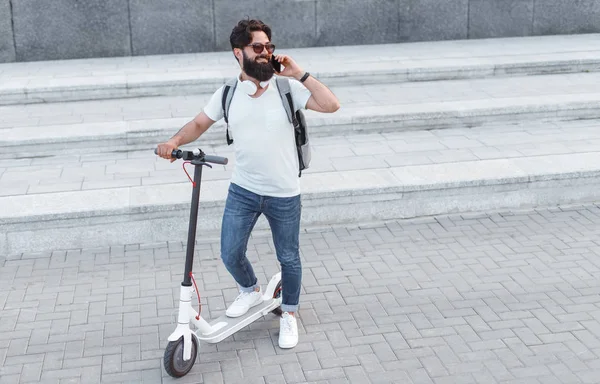 Hipster en scooter eléctrico hablando en smartphone —  Fotos de Stock
