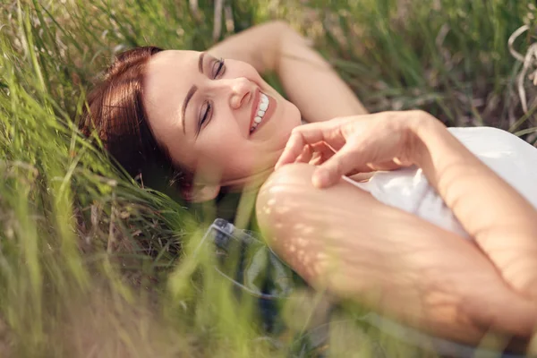 Mulher moderna alegre relaxando na grama do prado — Fotografia de Stock