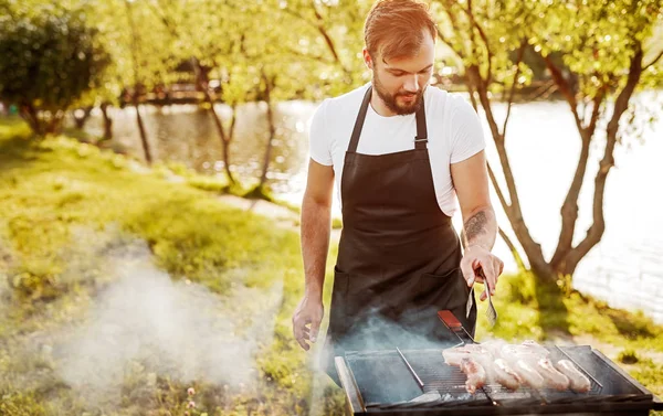 Chef smoking sausages on grill — Stock Photo, Image