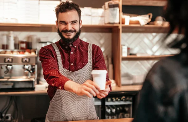 Веселий бариста, який подає гарячу каву клієнту в кафе — стокове фото