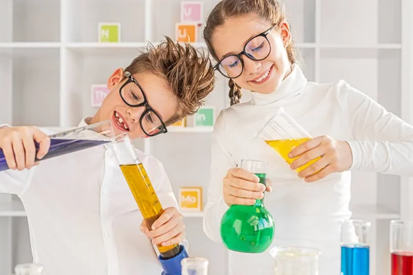 Companheiros entusiasmados fazendo experimentos com líquidos multicoloridos — Fotografia de Stock