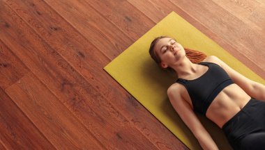 Peaceful woman meditating while lying down on floor clipart