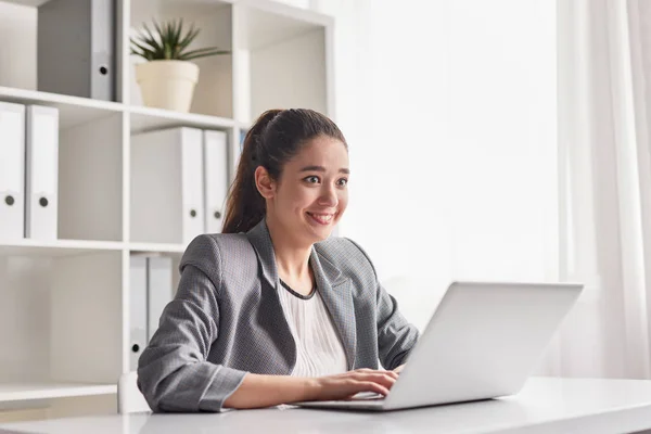 Jovem excitada usando laptop no escritório — Fotografia de Stock